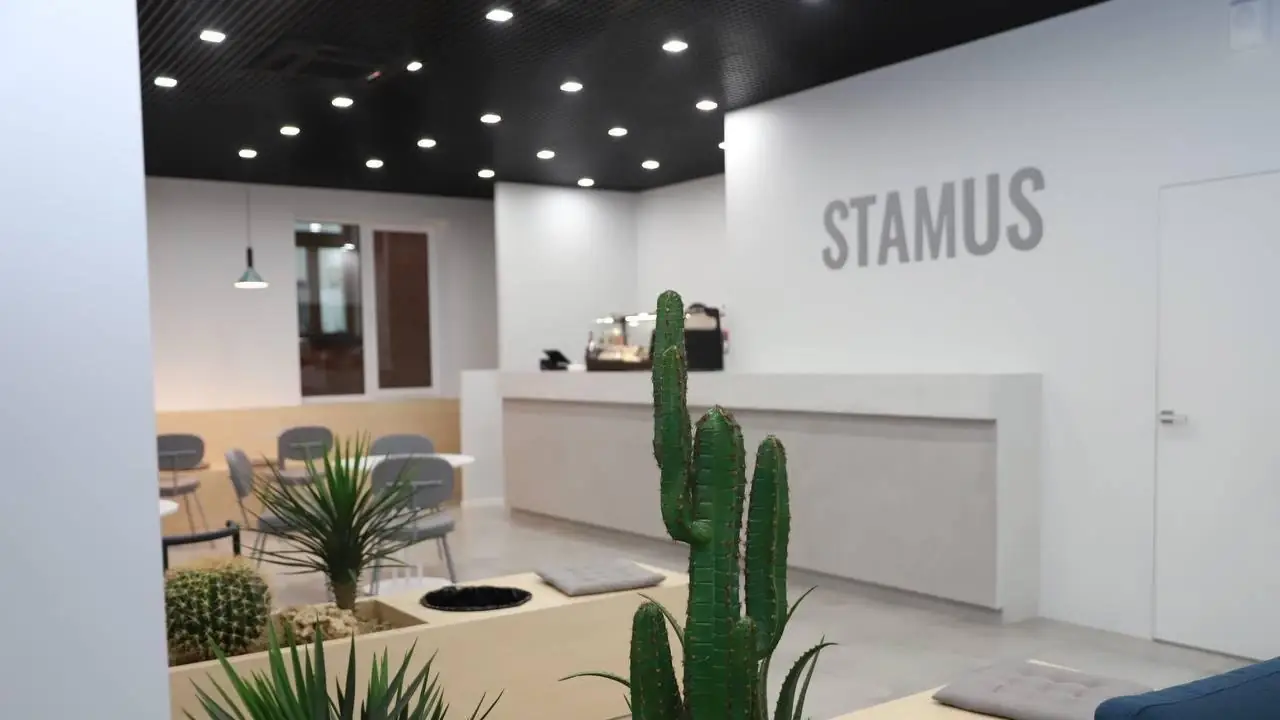 Стойка ресепшен с логотипом STAMUS и зоной с кактусами в интерьере