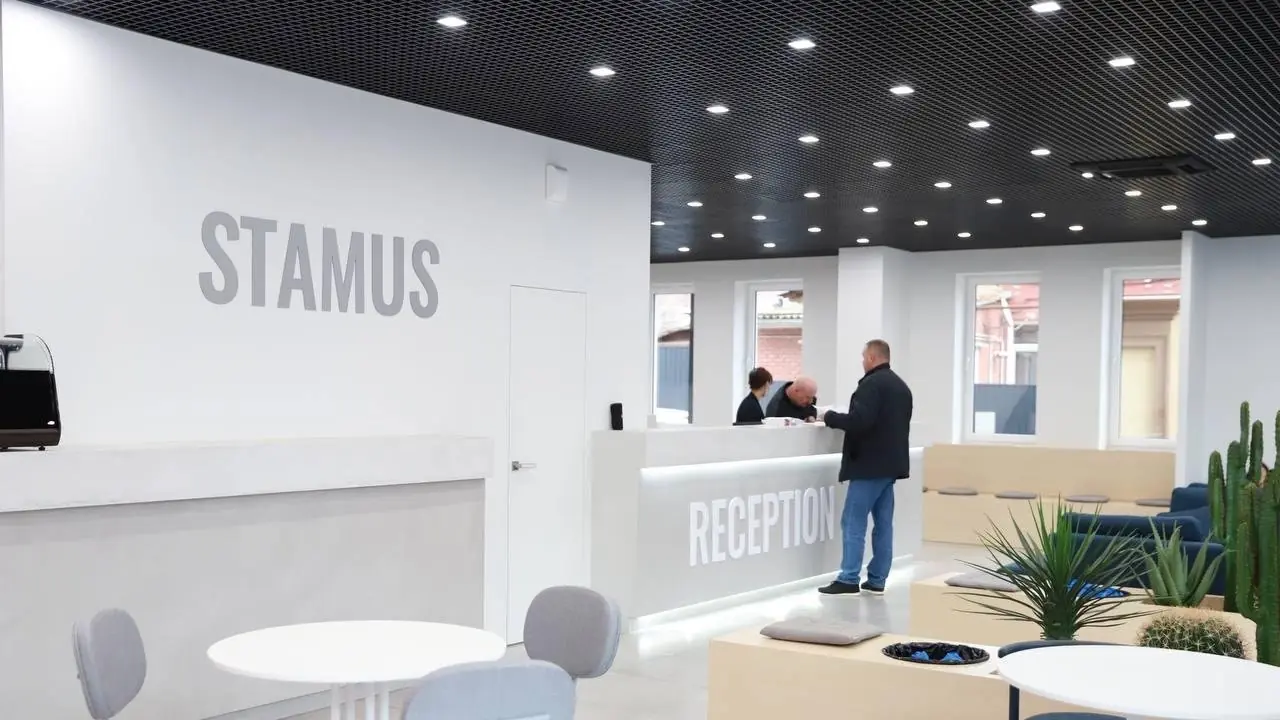 Пациент у стойки ресепшен STAMUS разговаривает с администраторами клиники